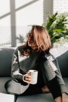 a woman sitting on a couch holding a coffee cup