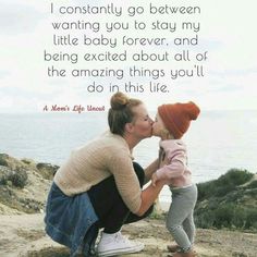 a woman kissing a small child on the cheek with an ocean in the back ground