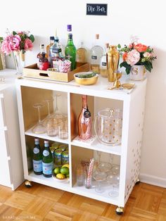 a white bar cart filled with bottles and glasses