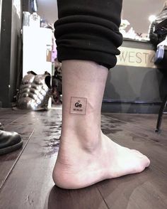 a person's foot with a small square tattoo on the side of their leg