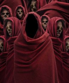 a group of people in red robes with skulls on their heads and hands behind them