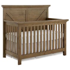 a wooden crib with white bedding and pillows on the bottom shelf, against a white background