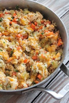 a pan filled with rice and vegetables on top of a wooden table