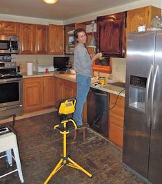 a woman standing in a kitchen next to a stove top oven and refrigerator freezer