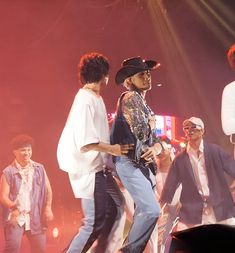 a group of people standing on top of a stage with one person wearing a cowboy hat