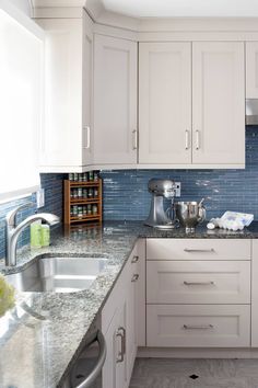 a kitchen with white cabinets and blue backsplash tiles on the counter top, along with stainless steel appliances