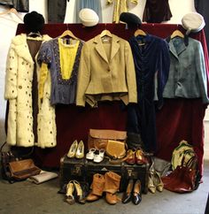 clothes and shoes are on display in front of a red cloth covered stand with several different types of clothing