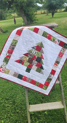 a quilted christmas tree sitting on top of a wooden chair in the grass next to a bench