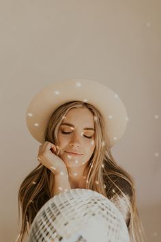 a woman wearing a white hat and holding her hand to her face