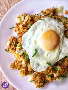 an egg is sitting on top of some fried meat and onions with scallions