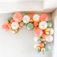 the balloon arch is decorated with pastel colors and gold, green, and white balloons