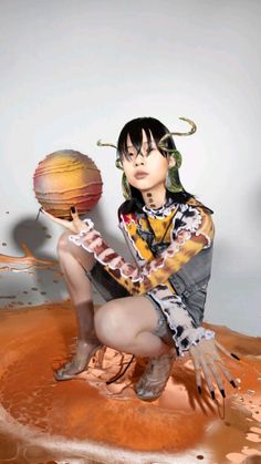 a woman holding a basketball in her hand and sitting on top of a puddle of mud