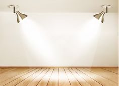 an empty room with two spotlights on the wall and wooden floor in front of it