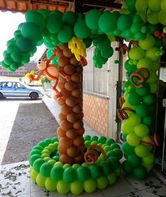 a balloon arch decorated with green and yellow balloons in the shape of a palm tree