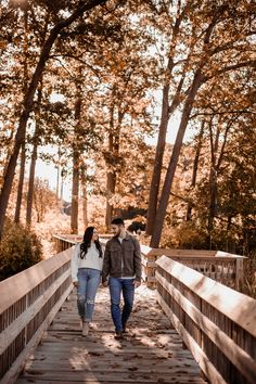 two people walking across a bridge in the woods