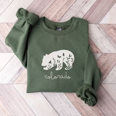 This Colorado bear sweatshirt is the perfect gift for the nature lovers in your life and it will be loved for years to come!  Its simple style will be sure to bring many compliments.  This unisex, heavy blend crewneck sweatshirt is pure comfort and will quickly become a favorite for Colorado dwellers and visitors alike! COLOR: This Gildan 18000 sweatshirt comes in several colors; just look at the drop down for options.   SIZING: These sweatshirts are UNISEX in size.  Please check the size chart in listing photos for best fit!   MATERIAL:  -Made from polyester and cotton with a ribbed knit collar, it retains its shape even after washing. There are no itchy side seams on these sweaters and the tag is tear-away.  -Using a medium-heavy fabric blend of 50% cotton and 50% polyester, this sweatsh State Sweatshirts, Tennessee Shirt, Bear Sweatshirt, Mountain Lover, Bear Mountain, Gatlinburg Tennessee, Blue Ridge Parkway, Bear Shirt, Colorado Rockies