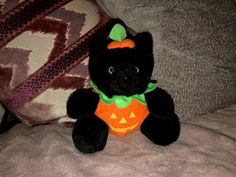 a black cat stuffed animal sitting on top of a bed