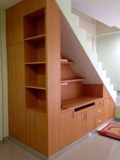 an empty room with some shelves under the stairs