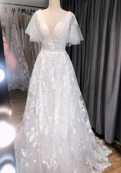 a white wedding dress on display in front of a mirror