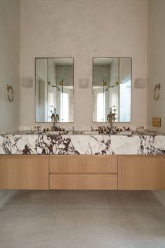 two sinks in a bathroom with mirrors above them and marble counter tops on both sides