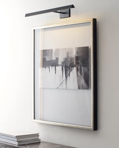 a black and white painting hanging on the wall next to a shelf with two books