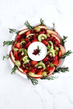 a platter filled with sliced fruit, kiwis and cranberry sauce