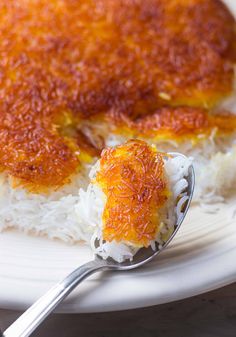 a spoon with some food on top of it next to rice and another dish that is covered in sauce