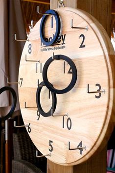 a wooden clock hanging from the side of a wall with numbers on it's face