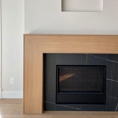 an empty room with a fireplace in the center and a framed photograph on the wall