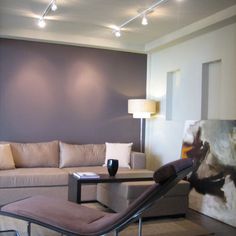 a living room filled with furniture and a painting on the wall next to a chair