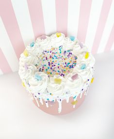 a cake with white frosting and colorful sprinkles on it's top