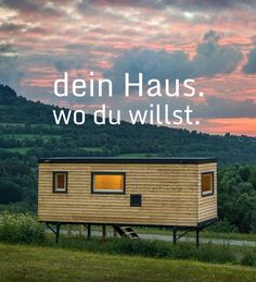 a small wooden cabin sitting on top of a lush green hillside under a cloudy sky