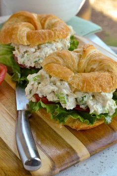 a sandwich with chicken salad and croissants on a cutting board