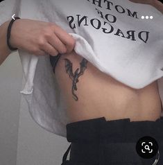 a woman wearing a white shirt with the words mother of dragons printed on her stomach