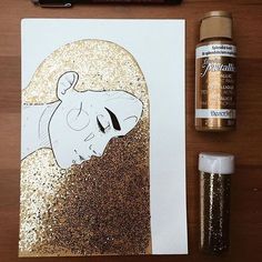 a painting with gold glitter next to it and some glue on the paper, including a bottle of paint