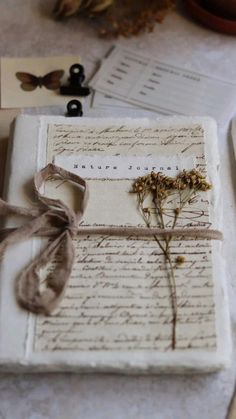 an old letter with a ribbon tied around it and some dried flowers on the table