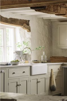 a kitchen filled with lots of white cupboards and counter top next to a window