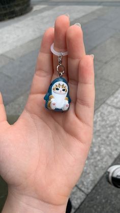 a hand holding a small keychain with a cat on it