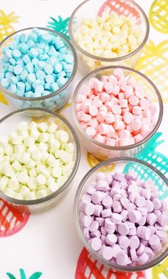 four glass bowls filled with marshmallows on top of a colorful table cloth