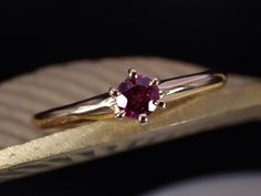 a close up of a ring with a pink stone in it on a gold plate