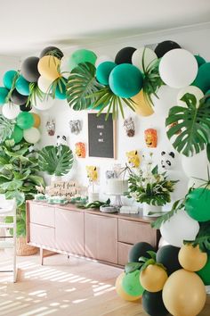 a room filled with lots of green and white balloons hanging from the ceiling next to a buffet table