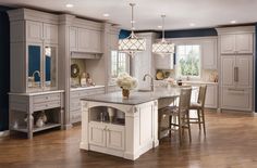 a large kitchen with wooden floors and white cabinets on the walls, along with an island in the middle