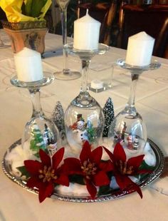 three wine glasses on a tray with candles and poinsettis in the center