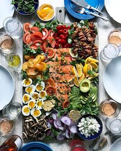 a table topped with plates and bowls filled with food next to utensils on top of a wooden table