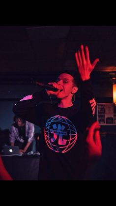 a man standing on top of a stage holding his hands up in front of him