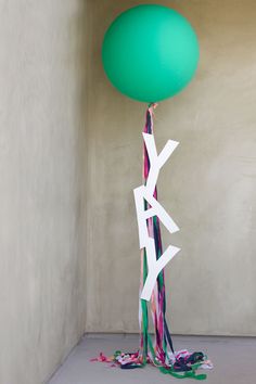 a green balloon sitting on top of a floor next to a white pole with streamers