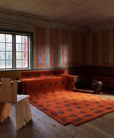 a living room with wooden floors and striped wallpaper on the walls, along with an orange rug