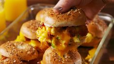 a person is holding up a sandwich with eggs and cheese on it in front of other sliders