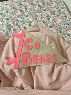 a sign that says go bears on top of a bed with pink sheets and pillows