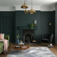 a living room with dark green walls and wooden flooring, two chairs, a coffee table and a fireplace